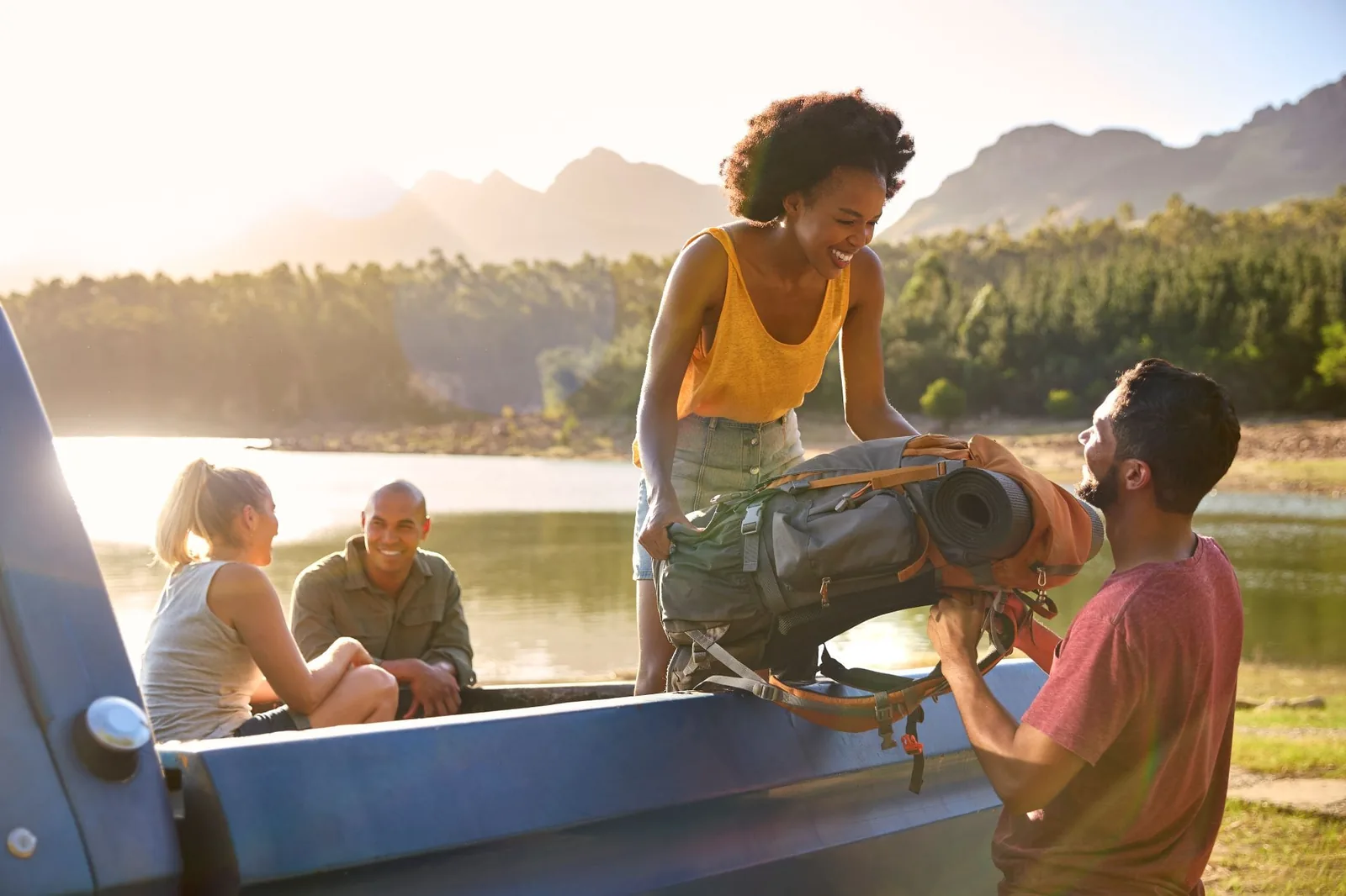 group-of-friends-unloading-backpack-from-pick-up-truck