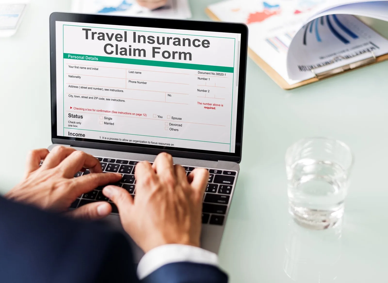 Hands of a White man filling out Travel Insurance Claim Form